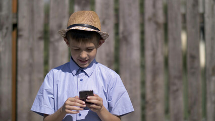 Fototapeta premium Boy in the hat uses the phone, have fun and enjoy