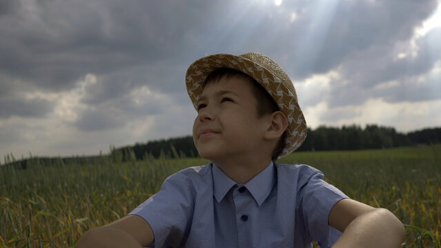 dreamer boy in the hat looks at the beautiful sky in the field, have fun and enjoy