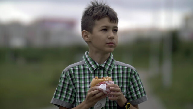 boy eats a burger in the evening in the street, have fun and enjoy