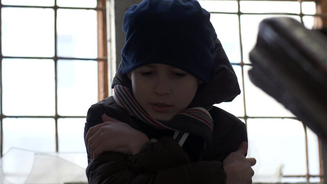 frozen wary boy is warming in a dilapidated old house, boy standing near a broken window, have fun and enjoy