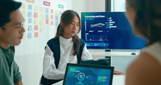 Group of Asian businesspeople work together discuss plan idea with investment data profit sale statistics in business meeting in office. Financial generation z team brainstorm on e-Commerce project.