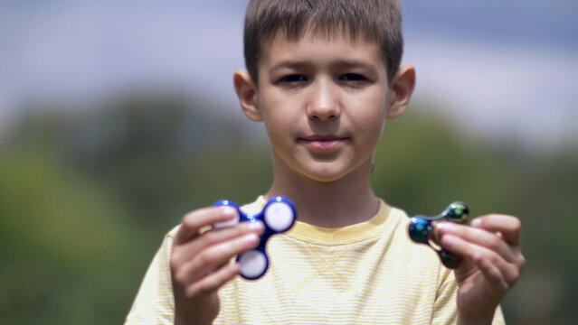 Happy Boy holding play two fidget spinners on nature, have fun and enjoy