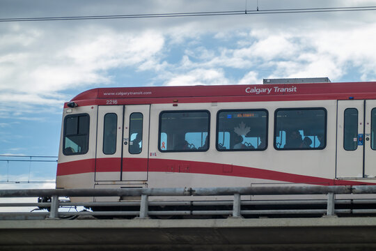 Calgary, Alberta, Canada. April 13, 2026. Side view of a red and white Calgary Transit C-Train light rail vehicle crossing a concrete bridge.