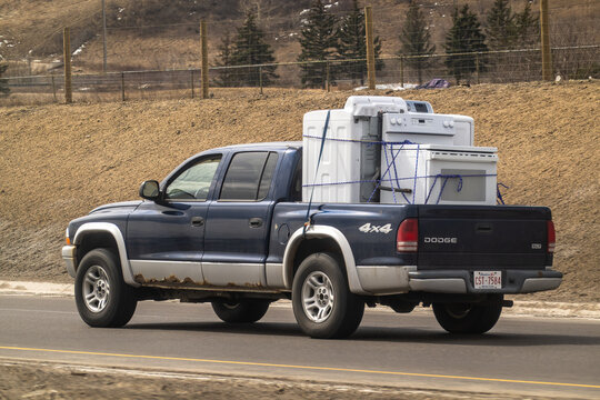 Calgary, Alberta, Canada. April 13, 2026. A blue Dodge Dakota pickup truck hauls a heavy load of used appliances on a highway.