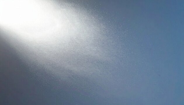 Un raggio di luce brillante attraversa un'atmosfera polverosa o nebbiosa, creando un effetto astratto e suggestivo su uno sfondo blu.