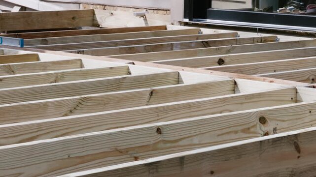 Wooden floor joists installed in parallel during construction of a deck or house frame. Structural framing stage. Move camera view