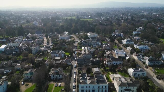 Aerial drone footage showcasing Monkstown Dublin Ireland suburban residential neighborhood with houses, streets, green spaces and cityscape.
