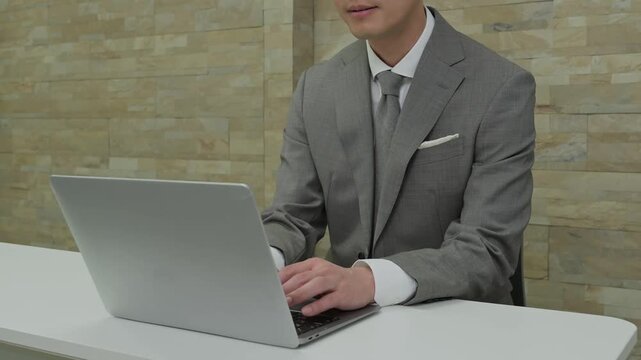 オフィスでパソコン作業をするスーツを着た日本人男性