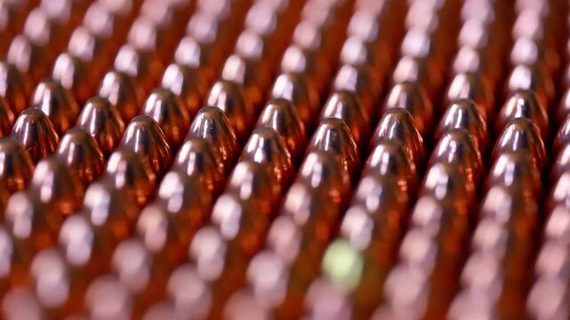 Rows of 9mm bullets rotating in circular formation. Close up of ammunition cartridges spinning with metallic shine