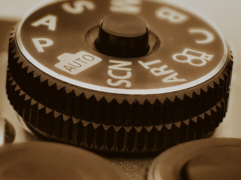 Macro close up of camera mode dial showing auto and scene settings with textured grip detail and warm lighting