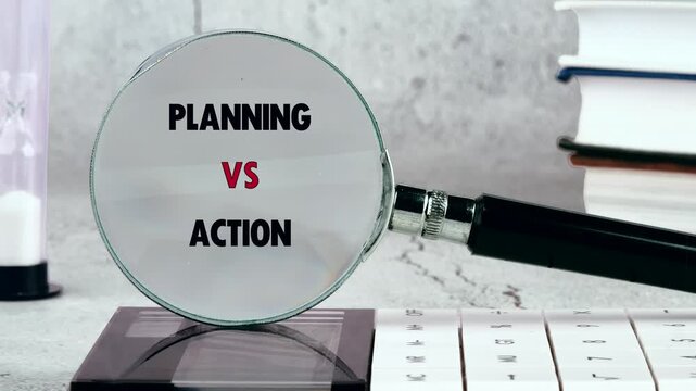 A magnifying glass focuses on the words planning versus action displayed on a desk, alongside books and an hourglass. This illustrates strategic thinking