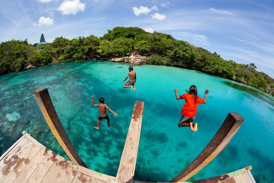 Three childrens jumping in Lake Waikuri, Sumba
