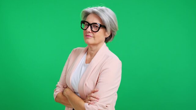 Confident senior businesswoman crossing arms on green screen