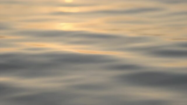 夕日の光を反射して柔らかく揺れる海面のクローズアップとボケ