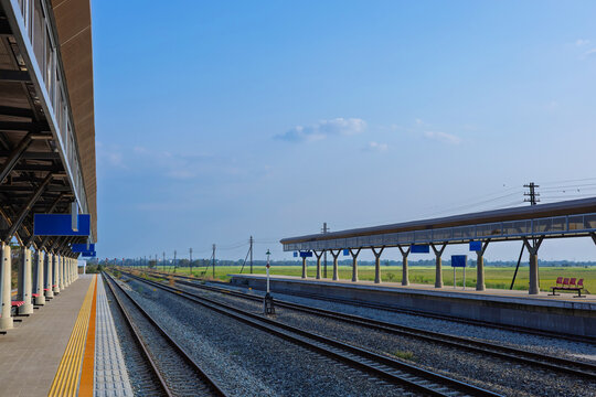 Perspective view of rural train station in beautiful countryside with railway tracks.