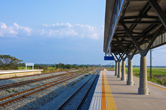 Perspective view of rural train station in beautiful countryside with railway tracks.