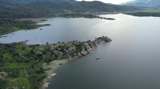 Drone footage captures the stunning natural beauty and historical significance of Bafa Lake Nature Park in Turkey. The aerial perspective showcases the serene waters of Bafa Lake nestled amidst rugged