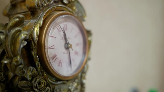Close up of an ornate vintage clock with a gold frame. The second hand sweeps across the classic face with Roman numerals, symbolizing the constant passage of time. Elegant and nostalgic