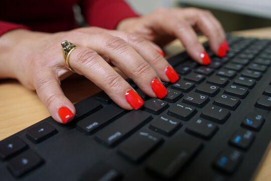 Woman secretary with red nails writing on a computer keyboard                               