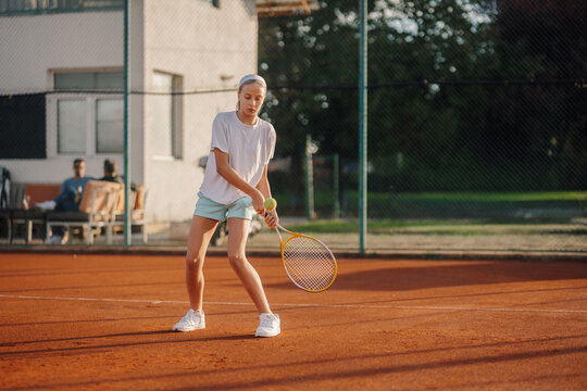 Young girl playing tennis on clay court