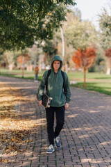 Fototapeta premium Young man walking through park holding a skateboard