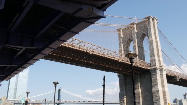Brooklyn Bridge from Manhattan Downtown, New York City, United States. Bridge to Dumbo from esplanade pier park in NYC USA. American architecture, famous tourist landmark. Waterfront urban promenade.