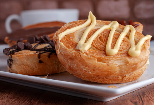 Reposteria casera, pan de hojaldre sobre un plato blanco para disfrutar en familia con cafe o leche, vainilla o crema pastelera