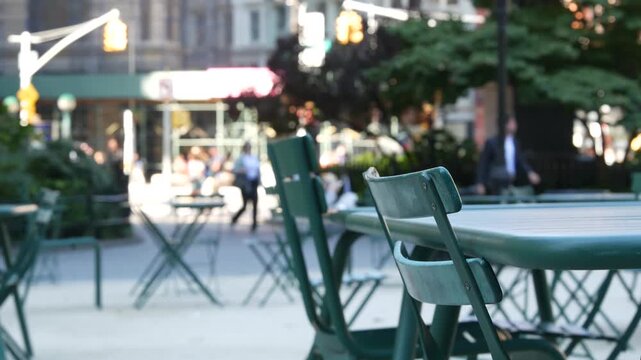 Fifth 5 avenue and Broadway street crossroad, Manhattan Midtown, New York City, United States. Defocused people pedestrians, chairs and tables for picnic in Madison Square Park, Flatiron District .