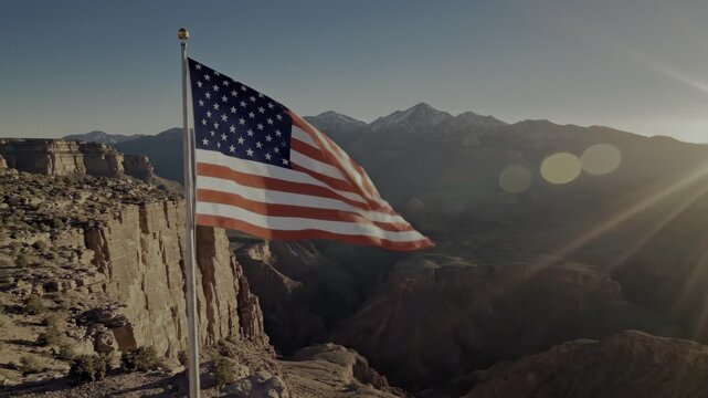 Patriotic American flag waving in a majestic mountain landscape during sunset, 4th of July Independence Day concept.