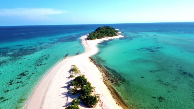 High-altitude drone photography of a tropical island paradise featuring a dramatic sandbank, colorful coral gardens, and the deep blue gradient of the open ocean horizon.
