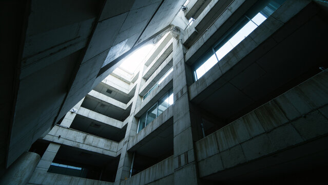 A dark and moody low-angle shot of an abandoned concrete building with stairs leading up to natural light