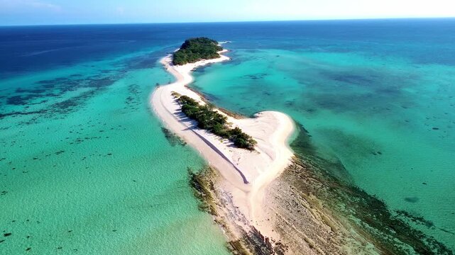Breathtaking drone shot of a remote island paradise with crystal-clear coral reefs and lush greenery.