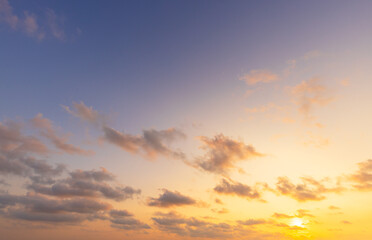 Fototapeta premium Golden Sunset over the Horizon with Soft Pastel Clouds,A breathtaking sunset scene featuring a vibrant golden sun dipping toward the horizon, illuminating scattered soft clouds with warm orange.