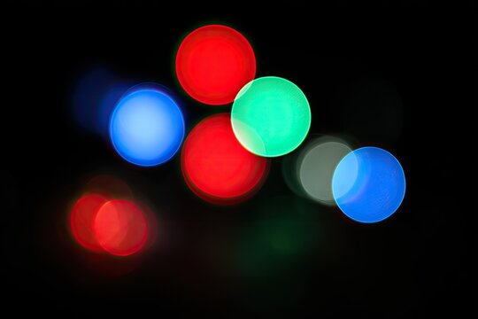 A captivating abstract image showcases vibrant, blurred circles of red, blue, and green light against a stark black background, creating a mesmerizing visual effect.