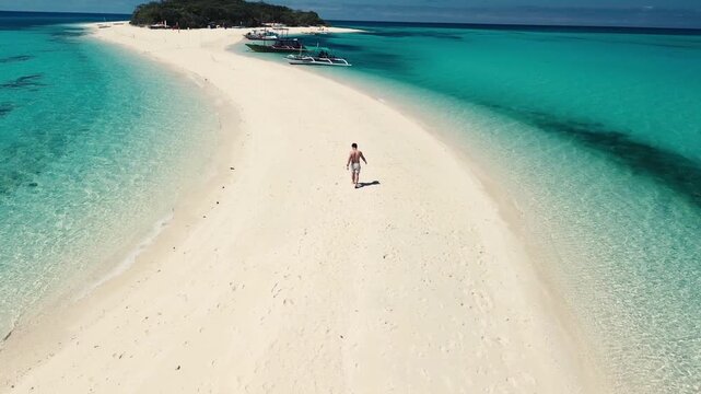 Solo traveler with arms outstretched on a remote tropical beach island at sunset..