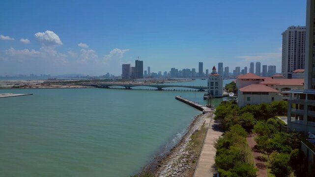 Kuala Juru river bridge connecting land reclamation and residential area with Georgetown city skyline and hills in background. Nice aerial view descending panorama drone