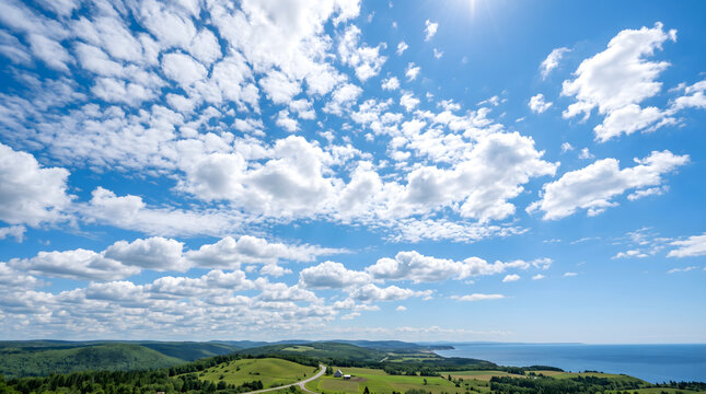Breathtaking wide-angle panoramic view of rolling green hills overlooking the deep blue ocean under a vast sky filled with fluffy white clouds