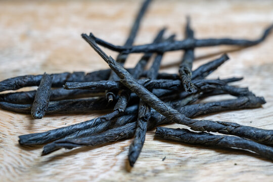 dried black tea leaves rolled into long, thin needles (kudin or needle tea), scattered on a light wooden surface