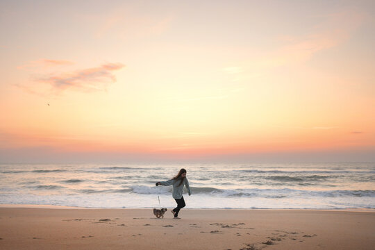 Tween girl running down beach with Shih Tzu puppy Outer Banks No