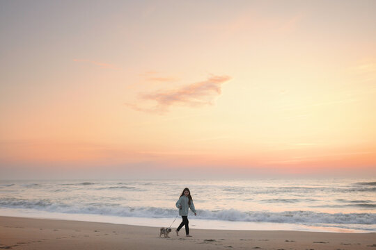 Tween girl walking Shih Tzu puppy on beach Cape Hatteras Nationa