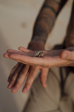 Hermit crab on tattooed man open hand palm close up on beach