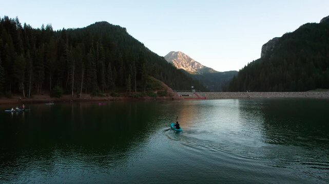 A Kayaker Glides Across Tibble Fork Reservoir Surrounded by Mountains in Utah, USA - Orbit Drone Shot