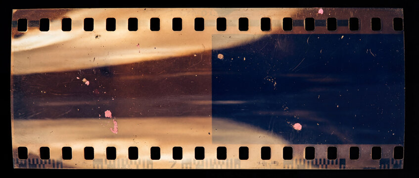 beginning of a 35mm film strip isolated on a black background, showing vintage analog texture, light leaks, scratches, and dust.