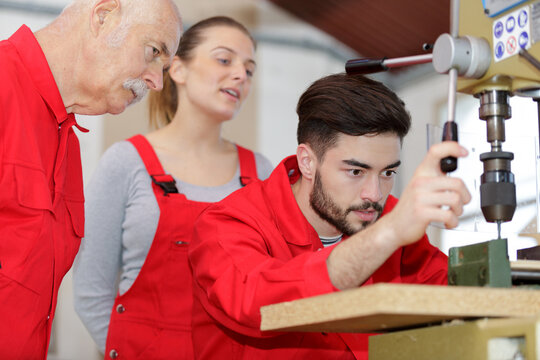 young industrial woodworker drilling a piece of board