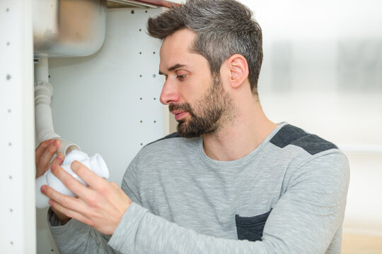man having an inspection under the kitchen sink