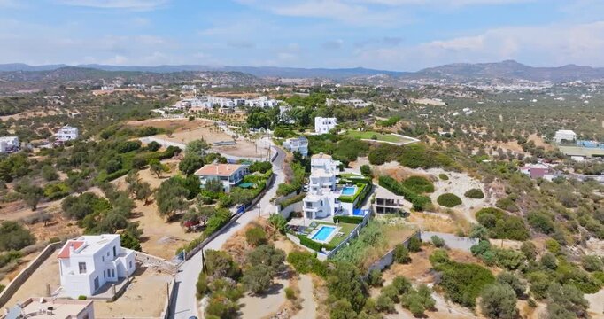 Aerial view approaching villas on a hill, sunny, summer day in Kolymbia, Greece