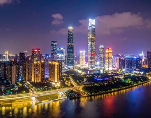 Fototapeta premium A stunning aerial view captures the vibrant cityscape of Shenzhen, China, illuminated at night with towering skyscrapers reflecting in the calm waters of the river.