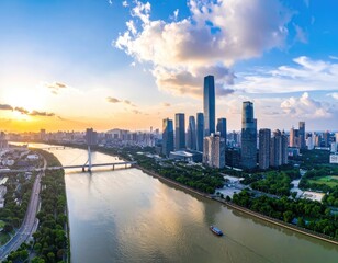 Fototapeta premium A stunning aerial view captures a modern cityscape nestled along a wide river, bathed in the warm glow of a vibrant sunset with fluffy clouds overhead.