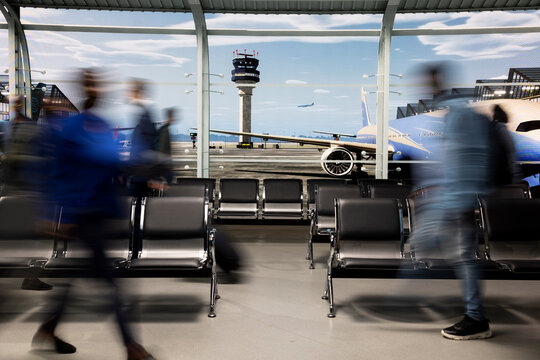 Walking rapidly, blurred motion and crowd in busy airport lounge. Navigating chaotic environment, long flight layover and group of passengers in transit hub before departure