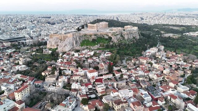 Aerial vista of the historic Acropolis in Athens, Greece, rising above the modern urban sprawl. A wide drone perspective of the ancient citadel and surrounding city neighborhoods